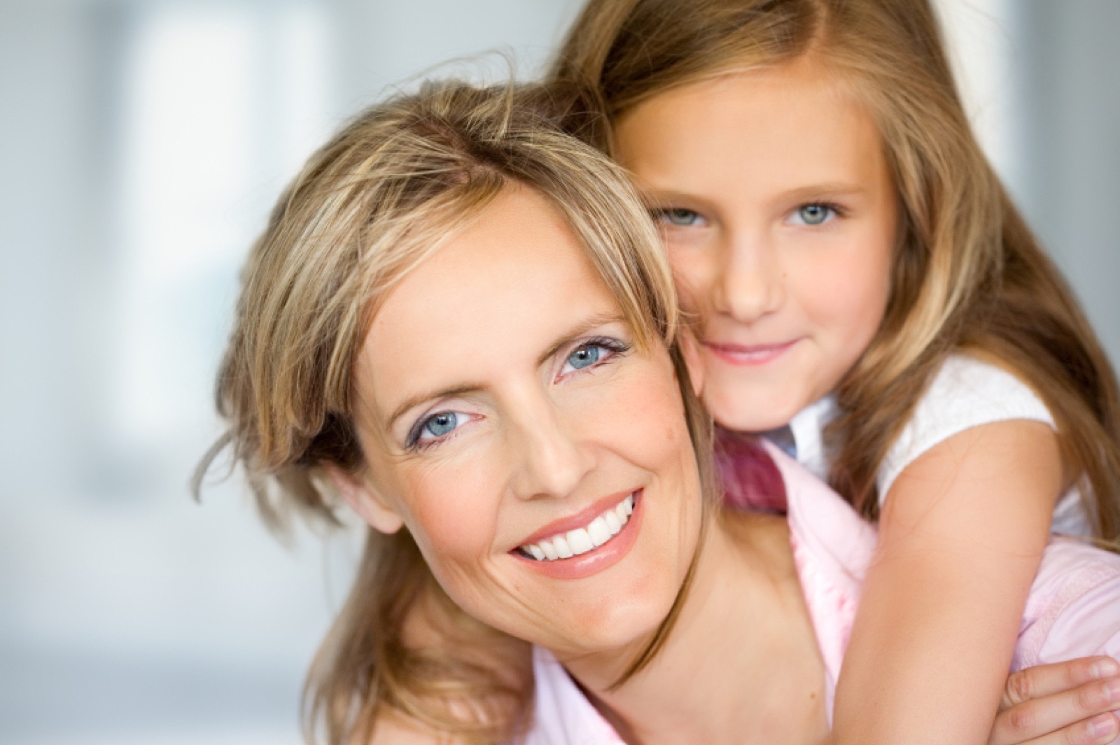 A mother and her young daughter smiling cheek to cheek