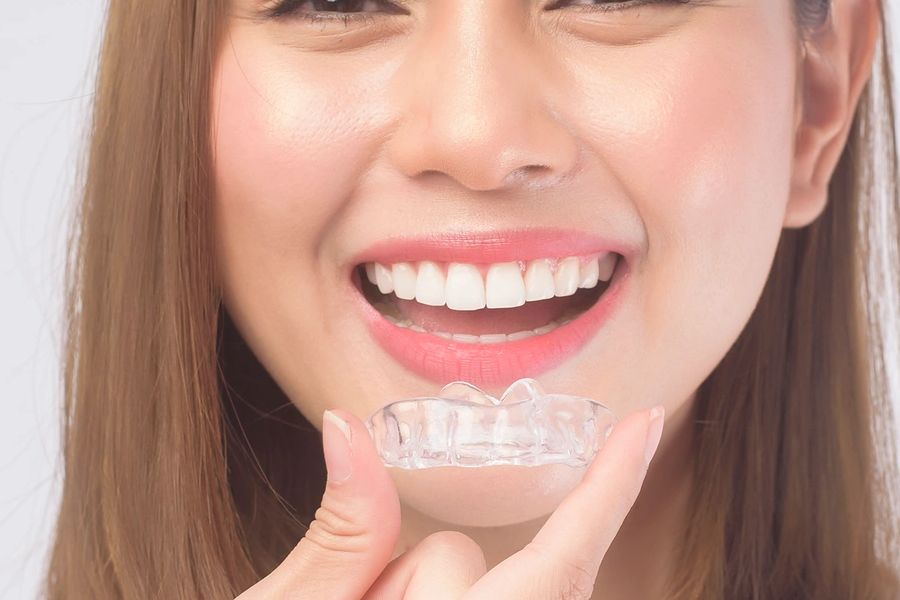 Woman holding Invisalign clear aligner tray