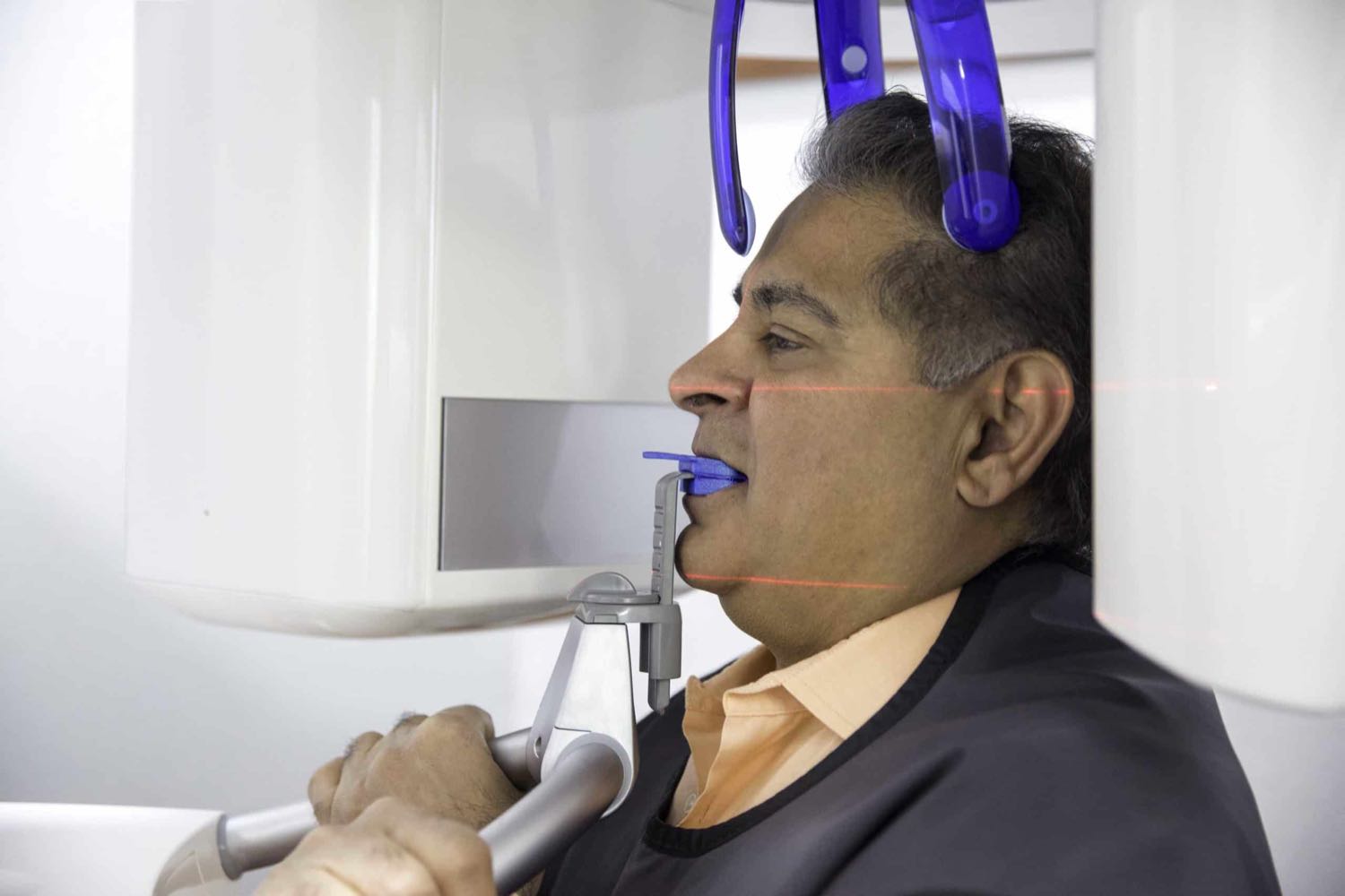A patient positioned in the practice's 3D scanner, with the alignment lasers in view