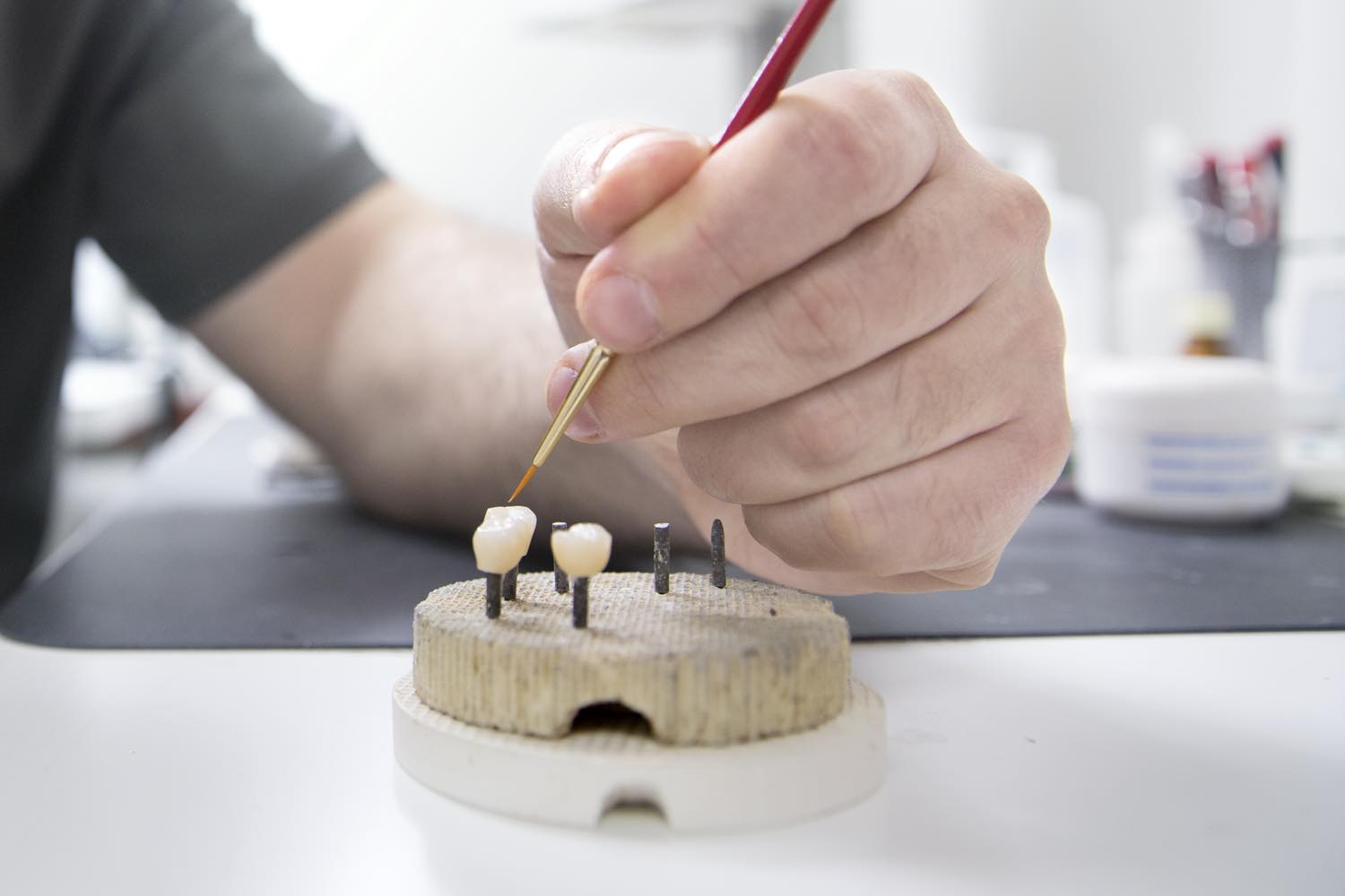 A technician hand-shading ceramic restorations in the in-house laboratory